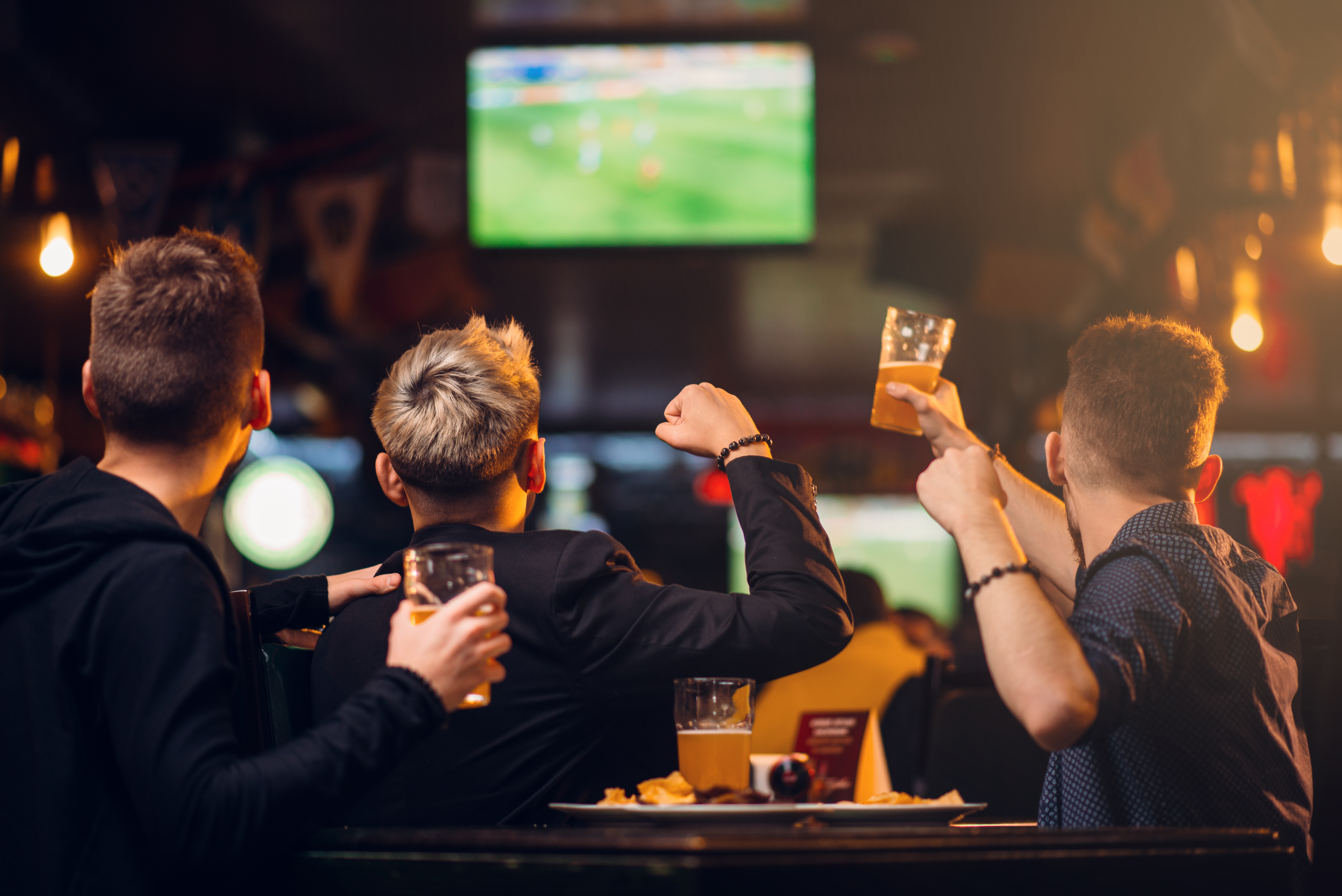 Three men watches football on TV in a sport bar